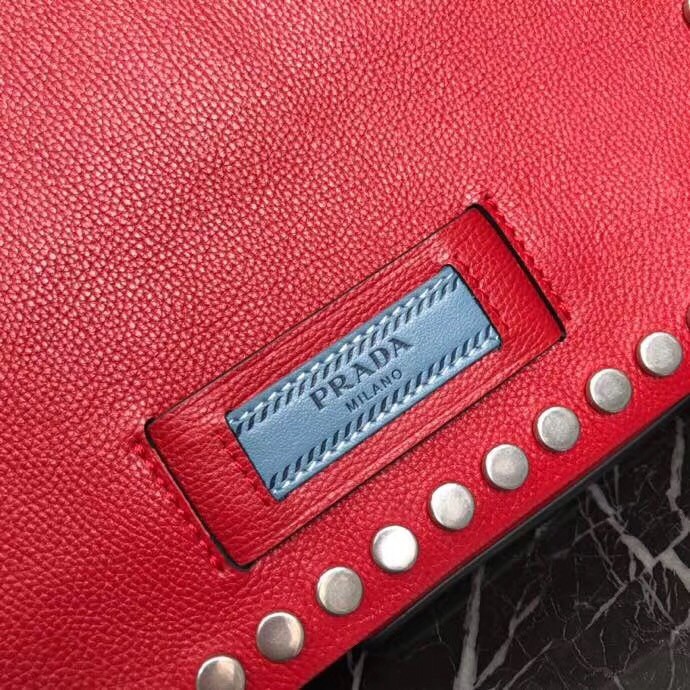 Pra*a etiquette bag in red calfskin with metal stud trim